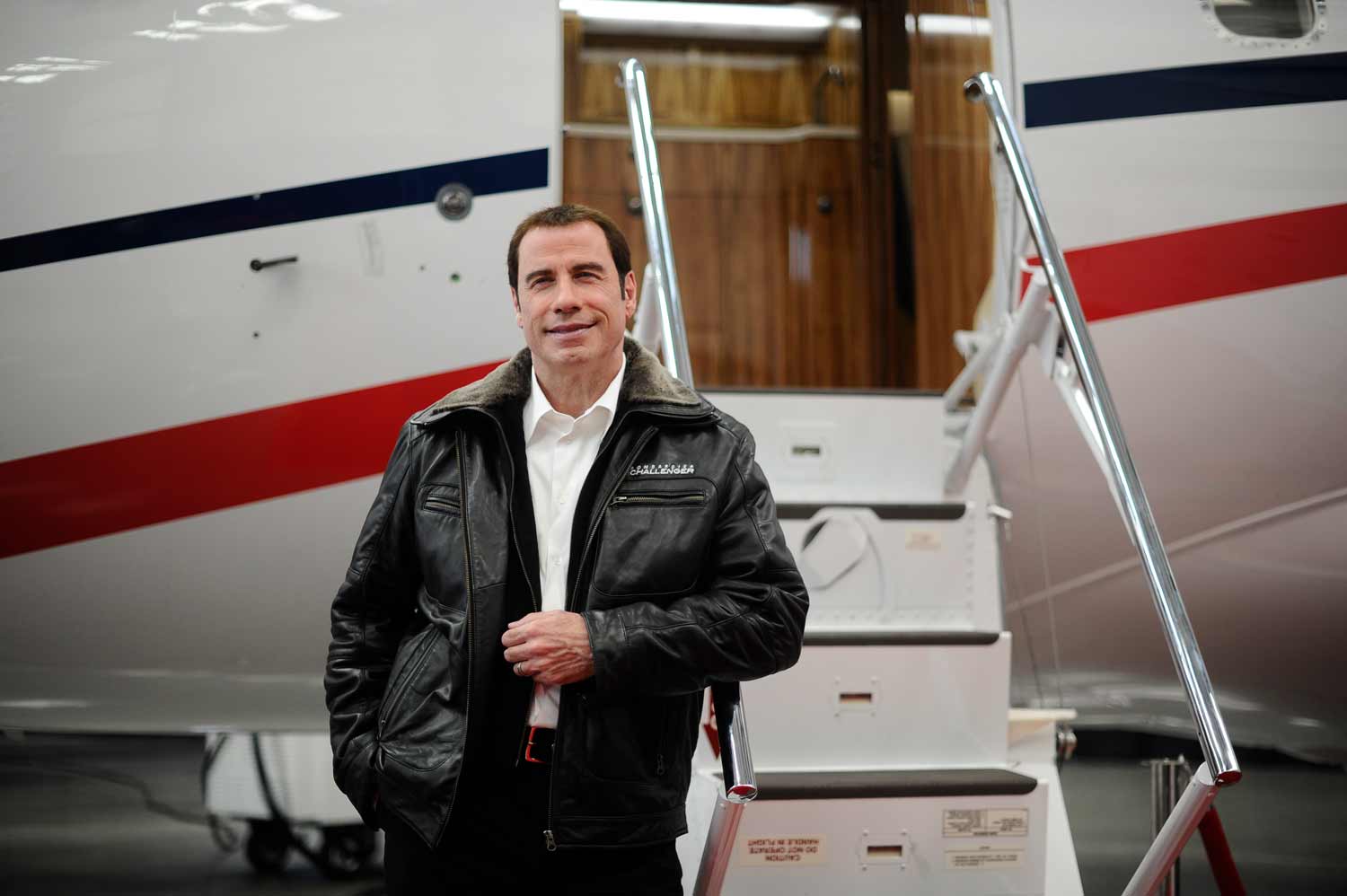 John Travolta standing in front of plane